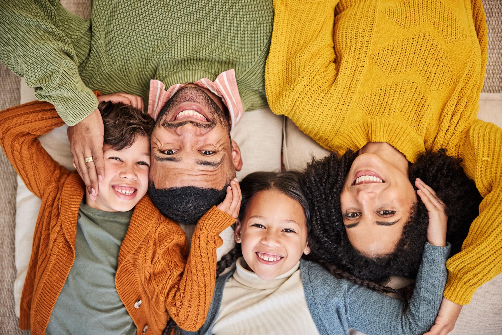 Top view, family and children in home with portrait, winter fashion or support with smile or foster care. Adoption, face or happy kids with love, jersey and warm clothes to relax on floor
