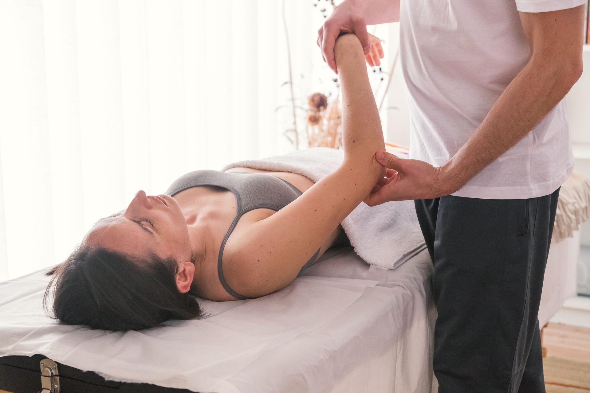 Young Caucasian woman being treated by therapist to help alleviate pain or improve physical condition. Therapist doing pressure and massage exercises to improve patient's health.