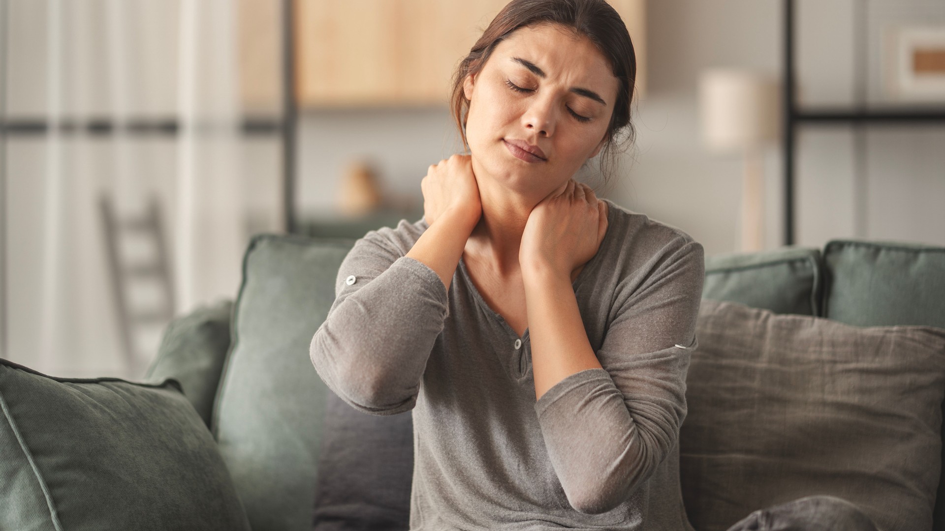 Woman suffering from neck pain in home