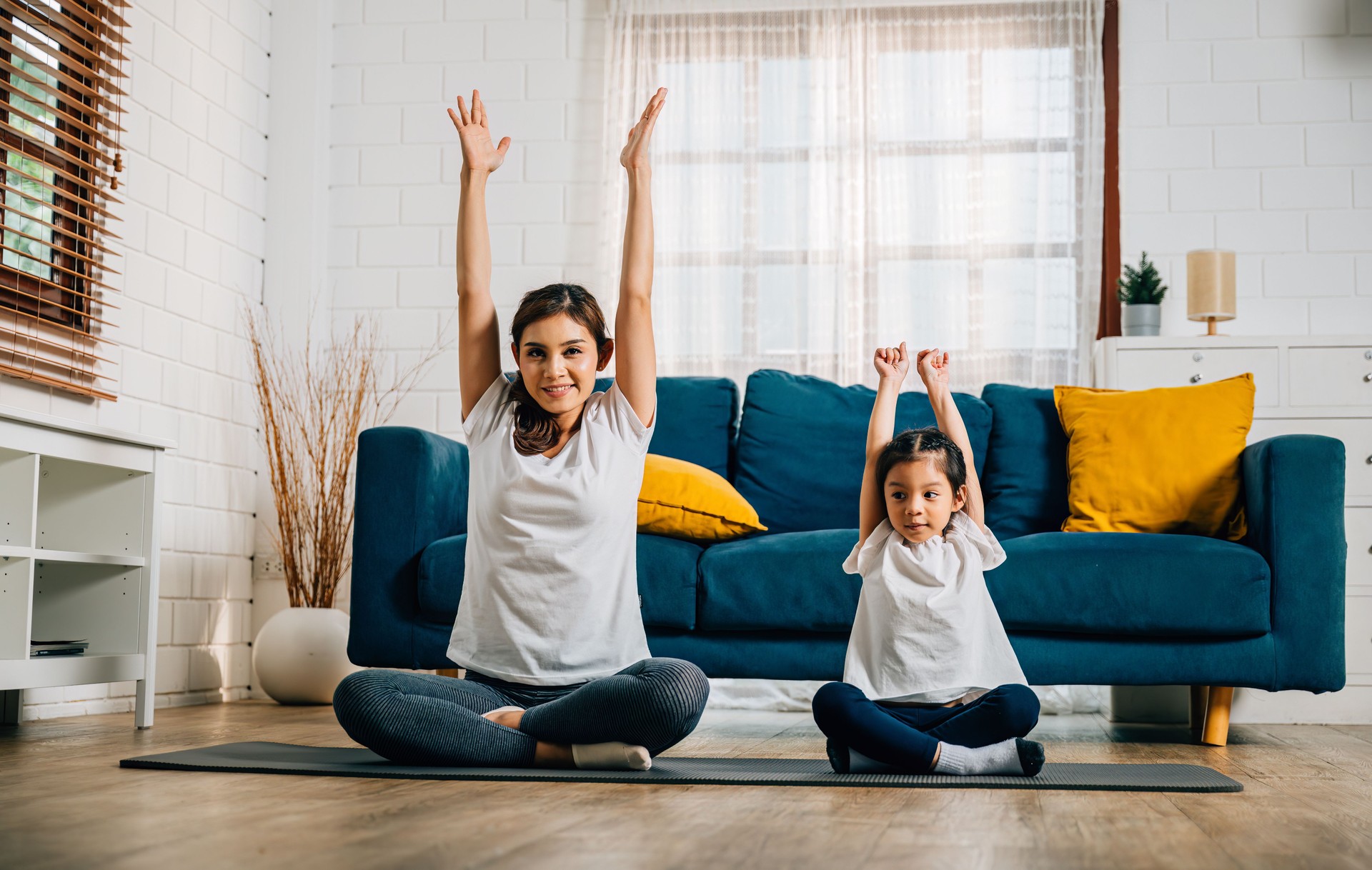 A mother teaches her daughter yoga focusing on stretch and balance in their home