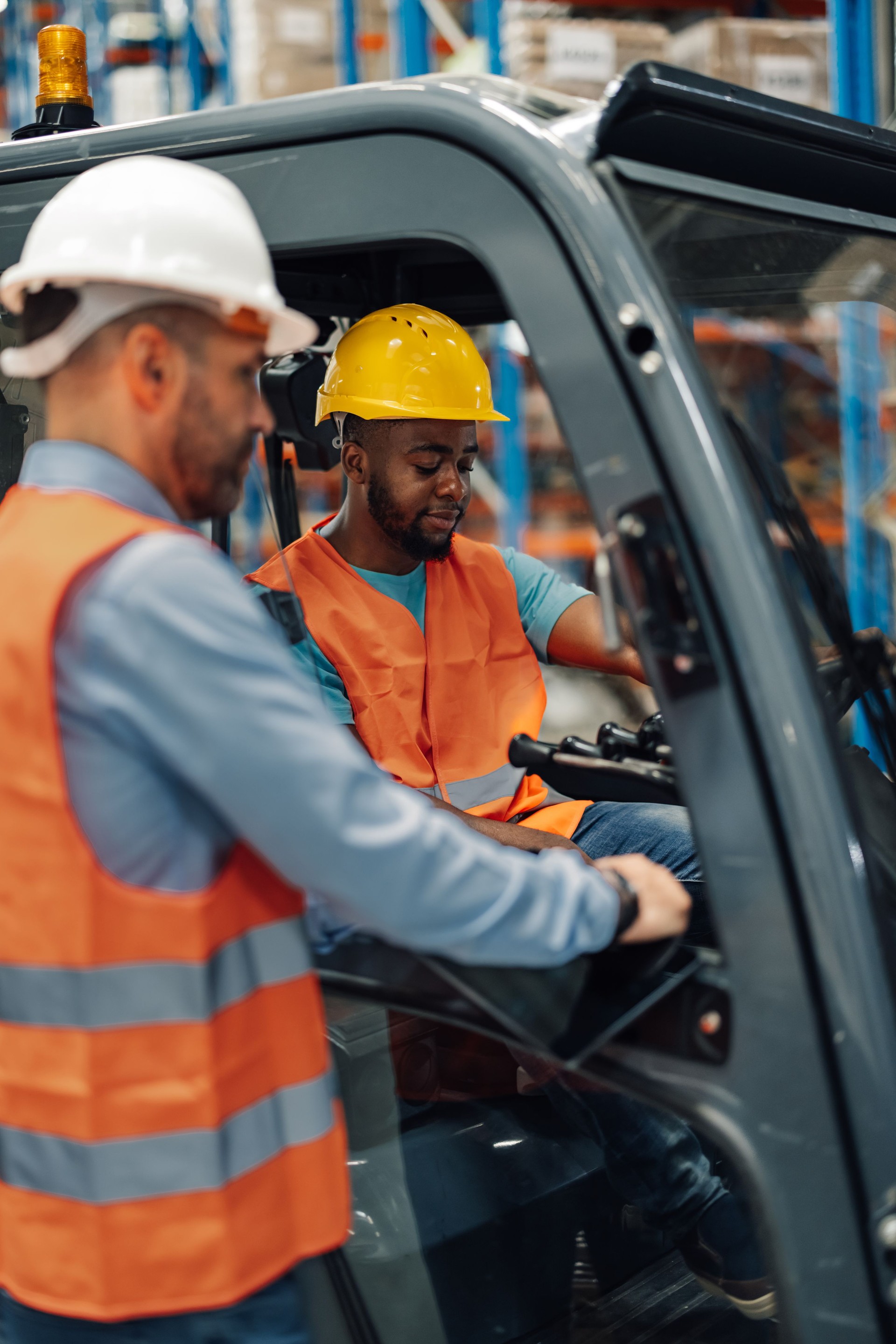 Warehouse manager explaining to driver using digital tablet while sitting on forklift in a warehouse