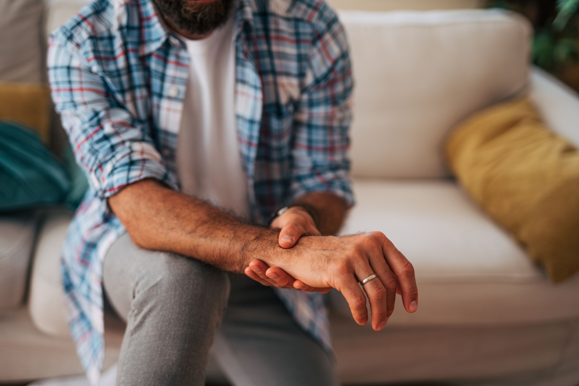 Man experiencing wrist pain while sitting on sofa at home